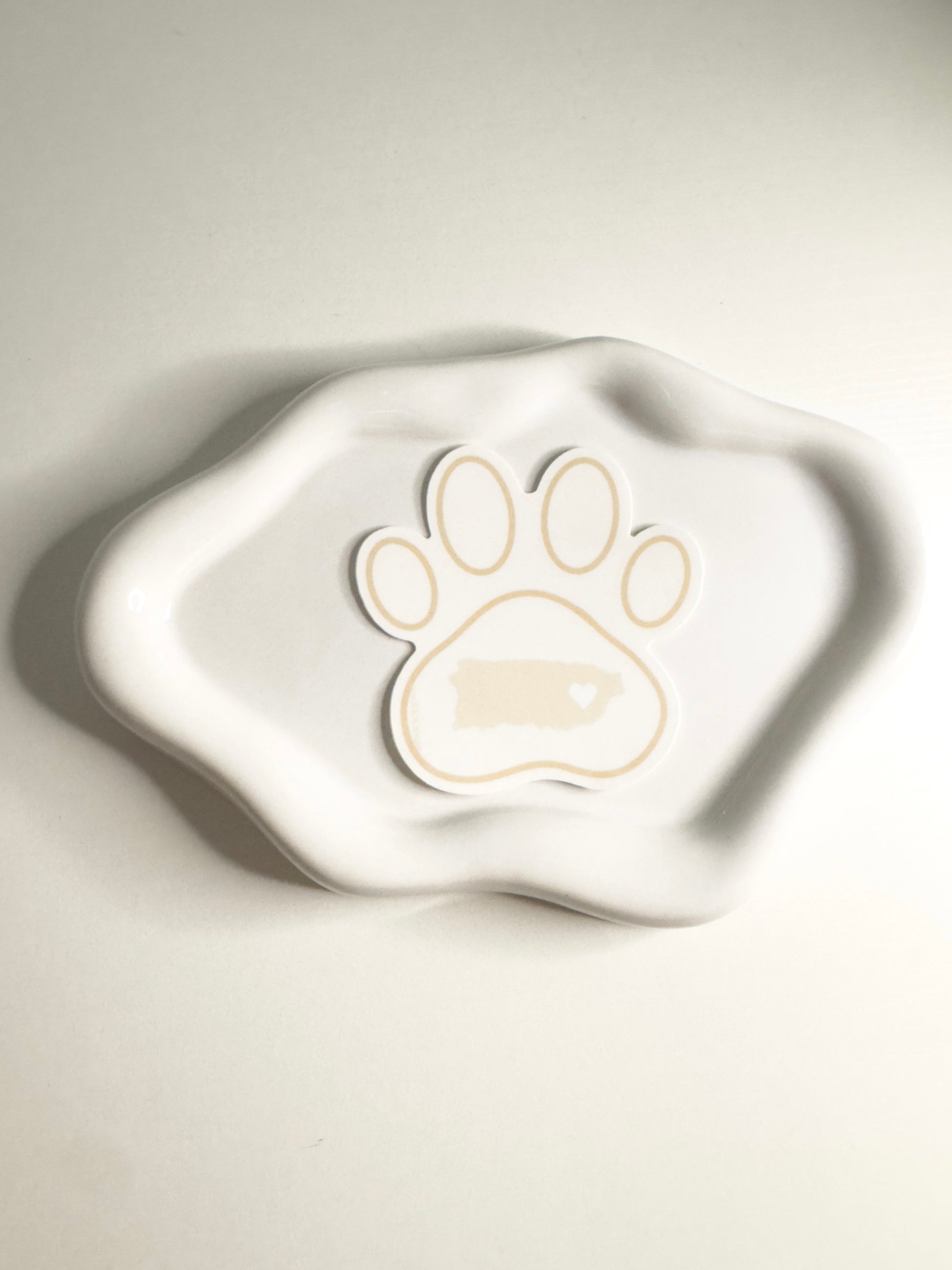White ceramic dish with a paw print design  of Puerto Rico on a light gray background
