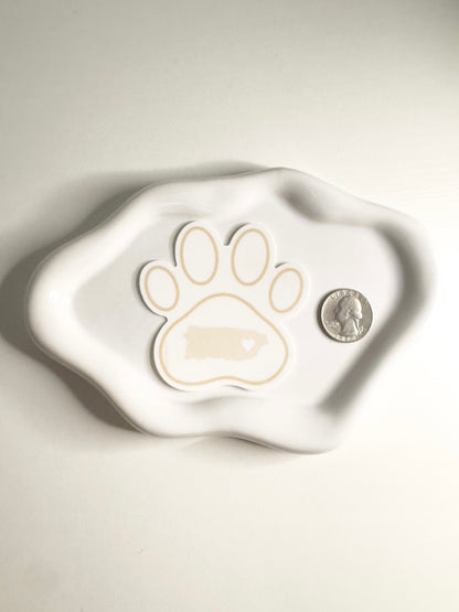 White ceramic dish with a paw print design of Puerto Rico  and a coin on a light background