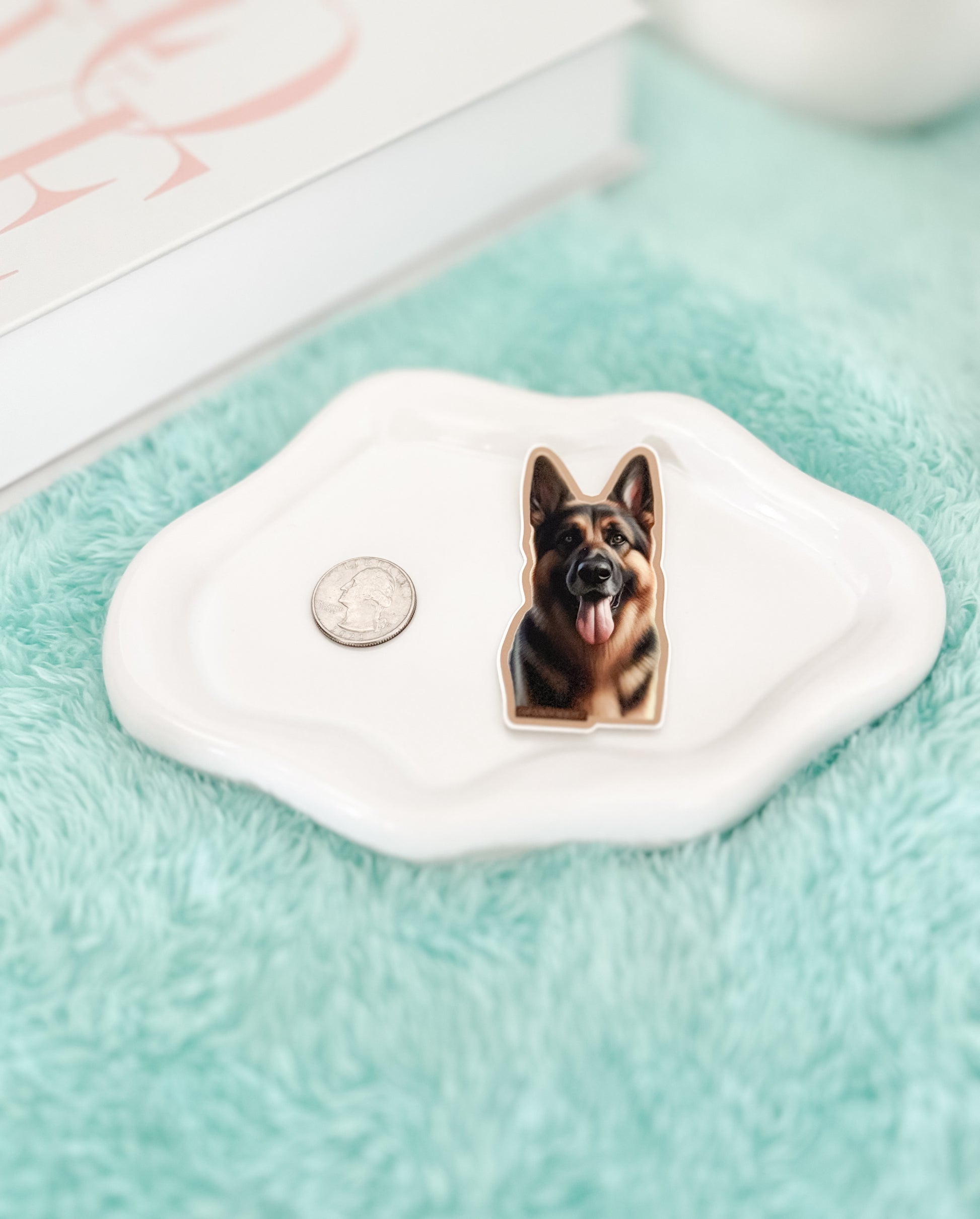 Dog-shaped keychain on a white stone with a coin next to it on a light blue surface.