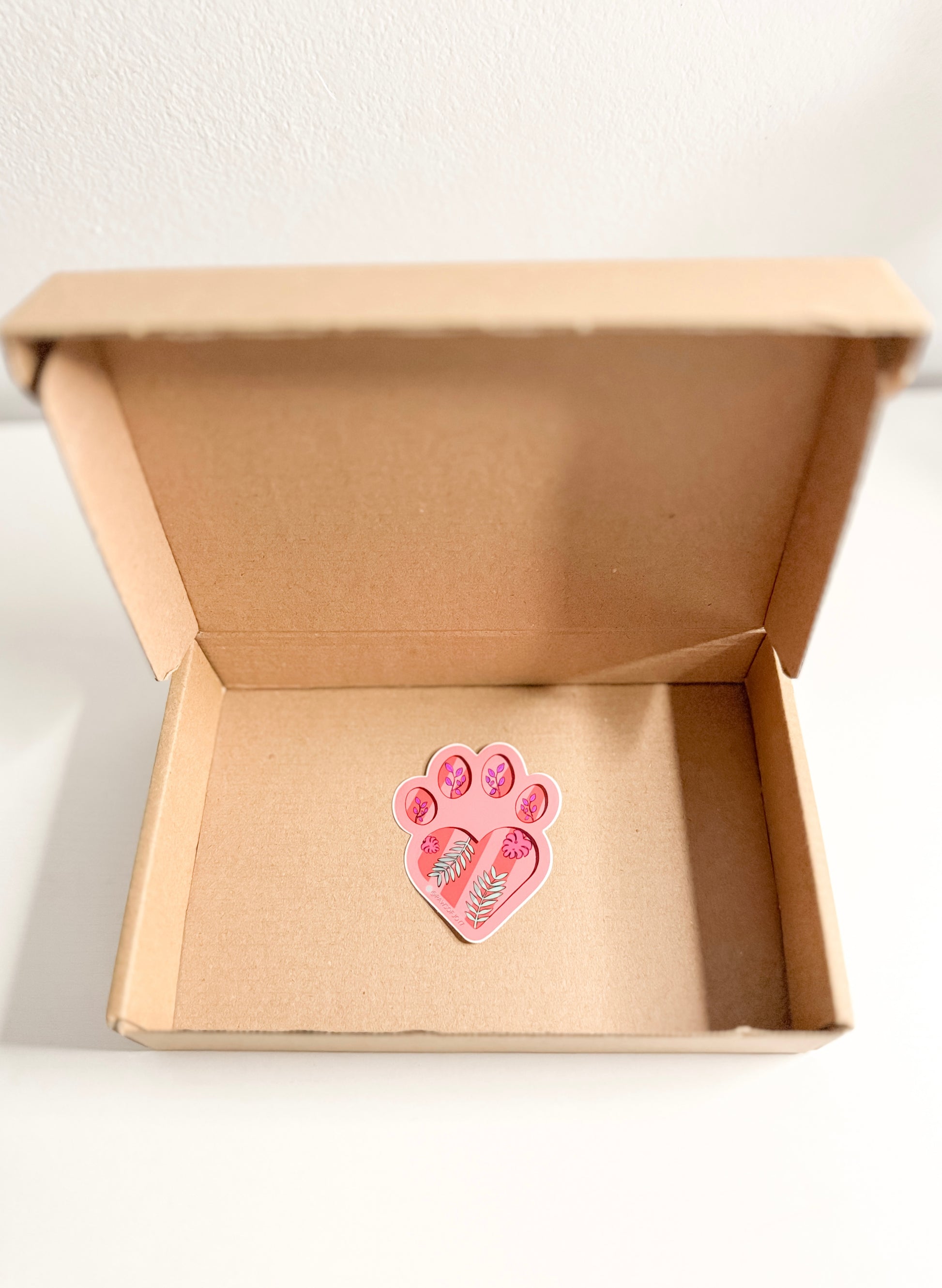 Pink paw print design in a cardboard box on a white background