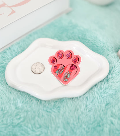 Pink paw print design on a white soap bar with a coin for scale, on a turquoise surface.