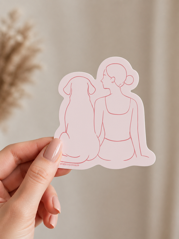 Hand holding a pink vinyl sticker of a woman and dog outline against a neutral background