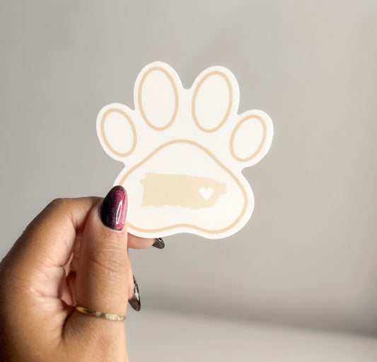 Hand holding a paw-shaped puerto rico map  sticker against a plain background