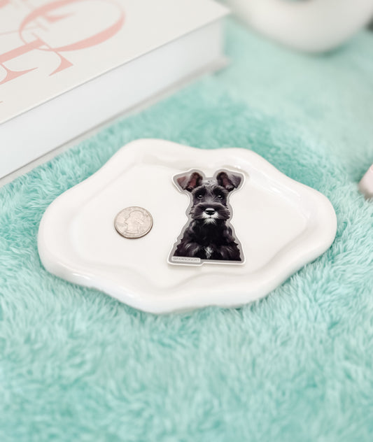 Small white dish with a black and white dog illustration on a green surface