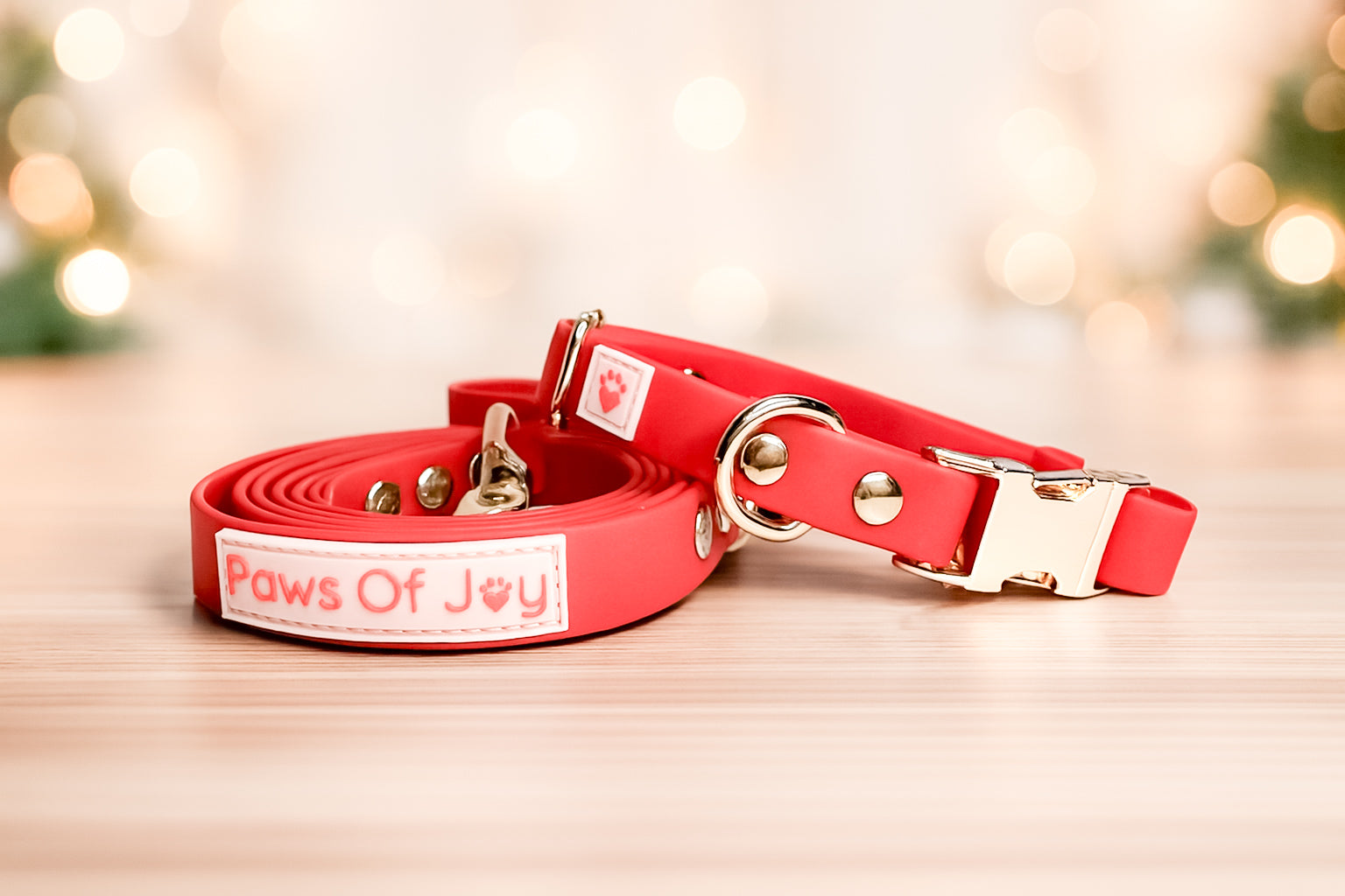 Red dog collar and leash set with 'Paws Of Joy' branding on a wooden surface.
