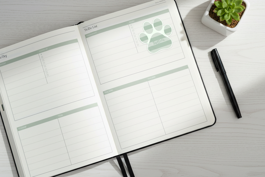 Open planner with paw print design on a desk with a pen and plant
