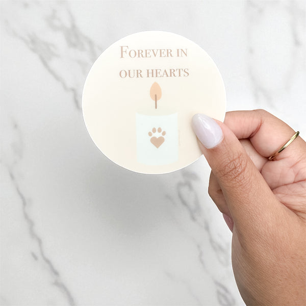 Minimalist vinyl sticker design with a glowing candle and a paw-shaped heart, reading “Forever in Our Hearts” — memorial pet sticker, 3x3 inches.